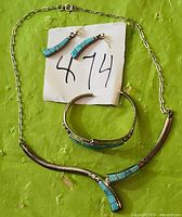 Photo showing the jewelry set with necklace, earrings, and bracelet displayed on green surface with lot number card visible.