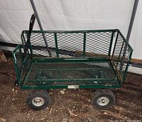 Green metal garden wagon cart with three metal mesh sides and one side missing, showing usage and metal frame.