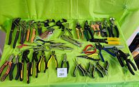 Overview of entire lot with various pliers, cutters, clamps, and other hand tools arranged on green cloth background