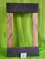 Front view of one padded wooden platform dolly showing gray fabric padding on wide ends of rectangular wooden frame.