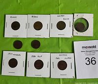 Nine Canadian small cents coins including blank and clipped planchets shown on green cloth background. Some coins are within hinged card holders with handwritten labels.