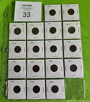 Sheet of 17 coins in cardboard flips laid out in three columns of six on green background with MaxSold tag
