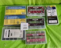 Overview photo showing seven partitioned plastic cases containing nuts, bolts, washers, hose clamps, and heat shrink tubing on green background.