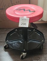Front angle view of the red padded seat stool showing worn surface and sticker tag.
