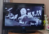 Toshiba TV displaying a black and white image of a speaker at a podium with text overlaid on the screen.