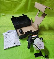 Wagner spray gun, power cable, funnel, owner's manual, and open carrying case on green background