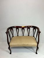 Front view of the lyre back settee showing upholstered seat and curved wooden frame with cabriole legs.