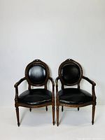 Front view of the pair of Louis XVI style French cabriolet armchairs showing oval backs and studded leather upholstery.