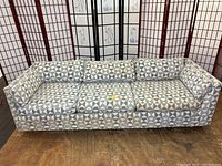 Front view of geometric patterned sofa with three seat cushions and straight arms.