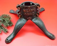 Front view of antique cast iron tree stand showing embossed 'A MERRY XMAS', patent info and maker's name.