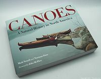 Front cover of the book 'Canoes: A Natural History in North America' showing canoe artwork on water and title in large red font.