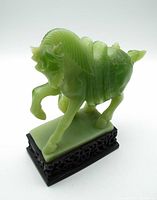 Front side view of the green faux jade Chinese war horse figure on dark carved wooden base, showcasing the figure's detailed carving and posture.