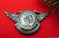 Front view of the vintage metal Saint Christopher visor badge showing detailed wing designs and the central medallion with Saint Christopher engraving.