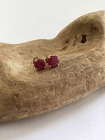 Close-up image of the ruby stud earrings displaying the bright red round rubies set in yellow gold.