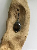 Full view of antique sterling silver pendant with smoky quartz set in the center surrounded by marcasite stones, placed in a wooden display.