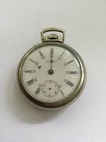 Front view of antique Waltham pocket watch showing white dial with Roman numerals, smaller 24-hour numbers, and seconds subdial
