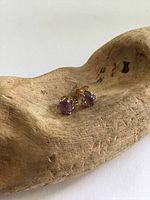 Pair of vintage gold filled amethyst stud earrings displayed on wooden surface, showing front view of purple amethyst stones in prong settings.