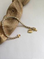 Full bracelet laid on driftwood, showing diamonds and heart charm