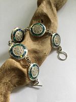 Front view of six round panels of bracelet with silver Mayan calendar motif and abalone inset.