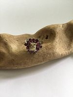 Front view showing sterling silver flower ring with garnets and central gold speck detail on wooden display
