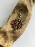 Front view of pendant showing ten marquise-shaped Baltic amber stones in varied colors set in sterling silver.