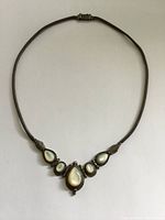 Front view of the full necklace laid flat on white background showing mother of pearl stones and silver chain