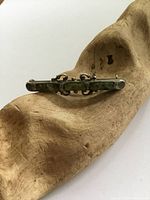 Front side of Victorian silver bar brooch displaying polished agate in rectangular setting, resting on textured wooden form.