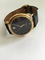 Front view of the ladies wrist watch showing the black dial with gold markers and hands, and gold-tone case.