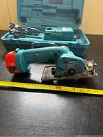 Cordless Makita hand saw with red battery pack, measuring tape for size reference showing approx. 14 inches length.