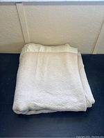 Folded beige Hudson Bay Baycrest bedspread with satin trim shown front side.