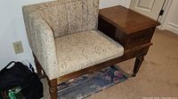 Retro telephone bench with beige and brown speckled upholstery and attached wooden side table with drawer, showing typical wear