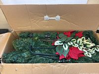 Photo showing artificial tree parts inside original cardboard box with floral and greenery components and metal stand.