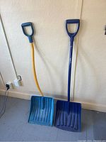 Two snow shovels side by side, showing their handles and scoops.