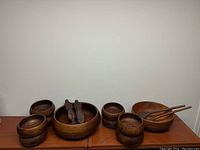 Photo showing both teak salad bowl sets and the carved wooden salad servers on a wooden surface.