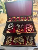 Full open view showing top and middle compartments filled with assorted jewelry