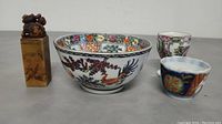 Lot of four items: porcelain bowl, egg cup, sipping cup, and soapstone stamp seen from front angle