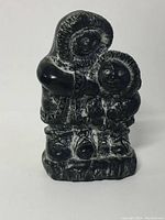 Front view of black resin Eskimo father and son carving, showing detailed traditional clothing and facial features.