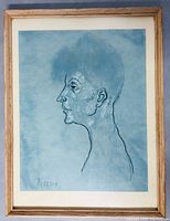Framed print showing male head in profile with blue background and light wood frame.