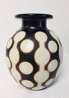 Front view of the black pottery vase with cream circular patterns and brown connection lines.