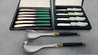 Photo showing the two boxed sets of knives and the two larger serving utensils in front.