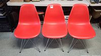 Three red Eiffel style chairs side by side, showing their overall shape and condition