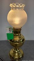 Full view of vintage Rochester brass table lamp with frosted embossed globe shade lit.
