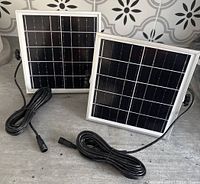 Two small solar panels, each 7x7 inches, shown with attached MC4 cables and mounting brackets.