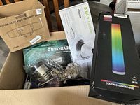 Top view of box showing LED color changeable lamp, leaf blower packaging, tangled cords, and motion activated security light box.