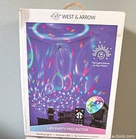 Photo of one sealed box of West & Arrow LED Party Projector showing product image with colorful lighting patterns and remote control on package front.