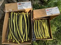 Two open cardboard boxes containing collated Quik Drive screws in yellow strips, nearly full.