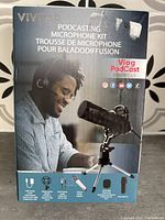 Front of the box showing Vivitar Podcasting Microphone Kit with image of microphone on tripod, listing included accessories.