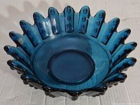 Angled front view of blue glass bowl with scalloped oyster and pearl edge.