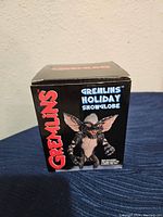 Front view of the black box featuring a Gremlin character and Gremlins Holiday Snowglobe branding.