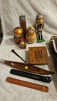 Overview of lot showing assorted collectibles including nesting dolls, nutcracker, wooden items, and grater